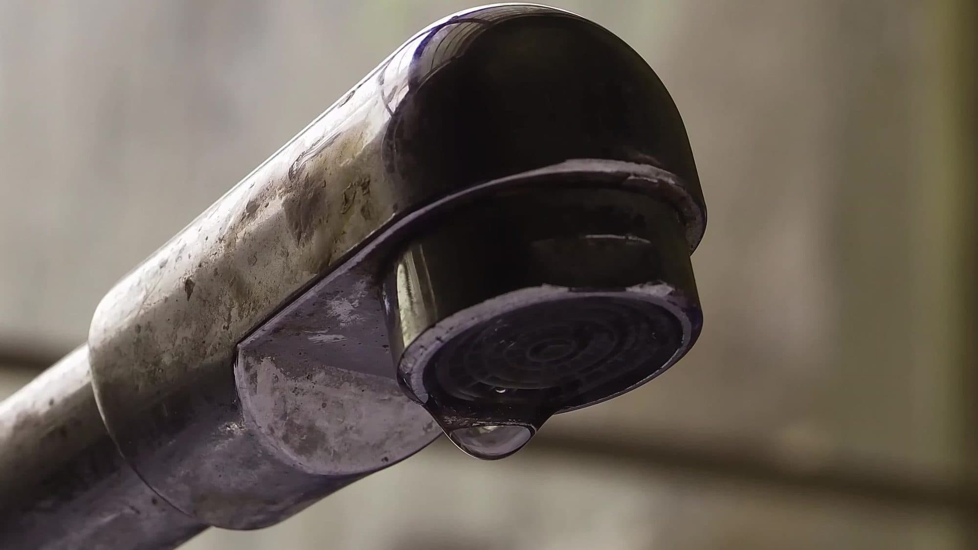 A metal tap with a drip forming